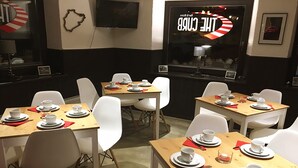 A dining area with tables set for four, white chairs, and a 'The Cup' sign in the background. -  DF am Ring Nürburg (Nuerburg)
