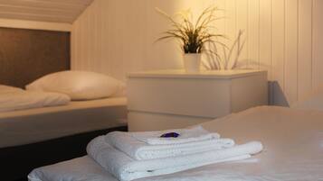 A neatly made bed with folded white towels and a potted plant on a bedside table.