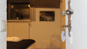 A bedroom with a bed, a chair, and a door with a key lock. -  DF am Ring Nürburg (Nuerburg)