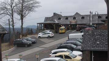 A parking lot with several cars parked in front of a building with a sloped roof and a signboard.