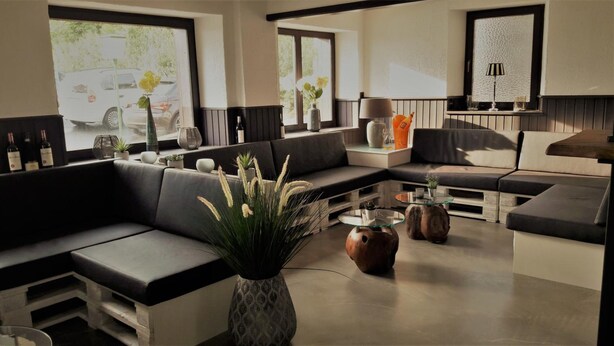 A modern living room with a sectional sofa, a glass coffee table, and a vase with plants. -  DF am Ring Nürburg (Nuerburg)