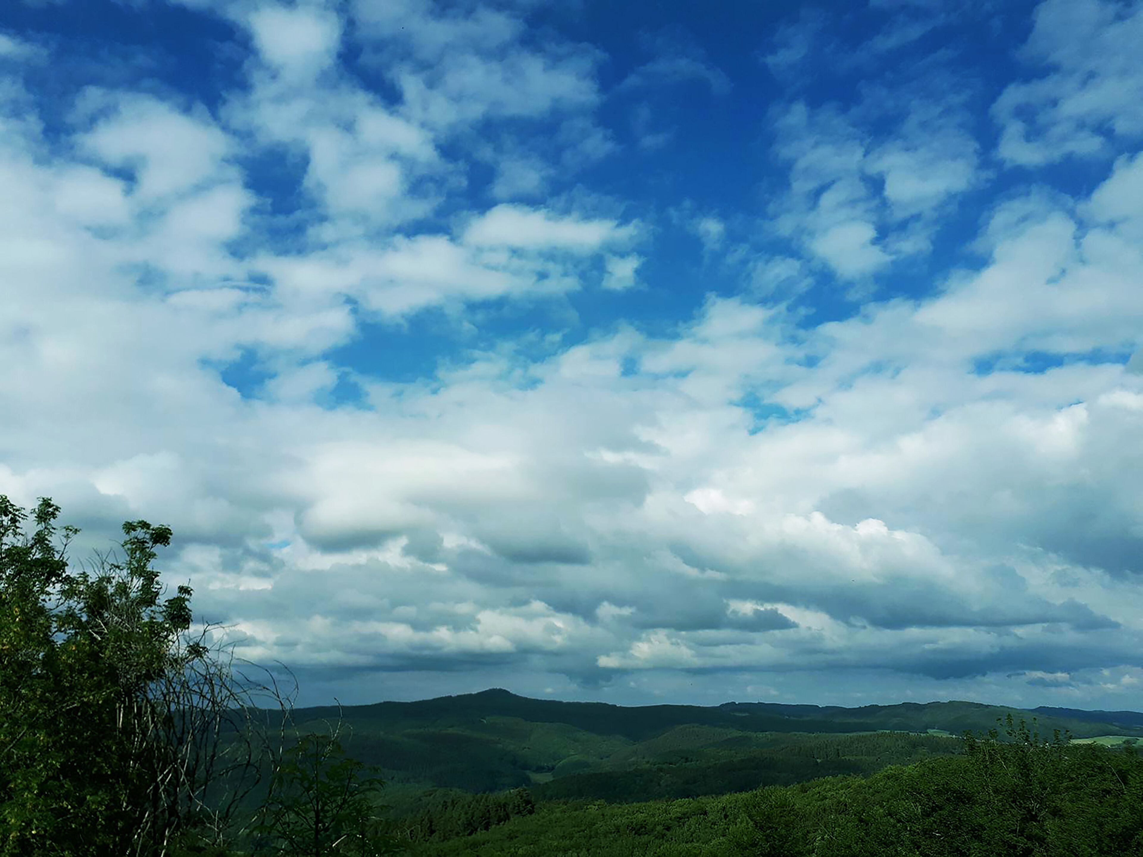 Un paysage de collines douces sous un ciel partiellement nuageux.