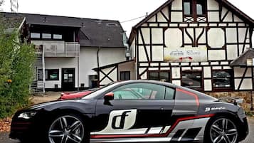 Une voiture de sport noire est garée devant un bâtiment traditionnel à colombages, sur lequel on peut lire l’inscription « The Lounge ».