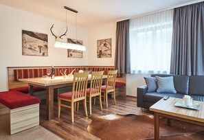 Un salon moderne avec un coin repas, des meubles en bois et des œuvres d’art accrochées aux murs.