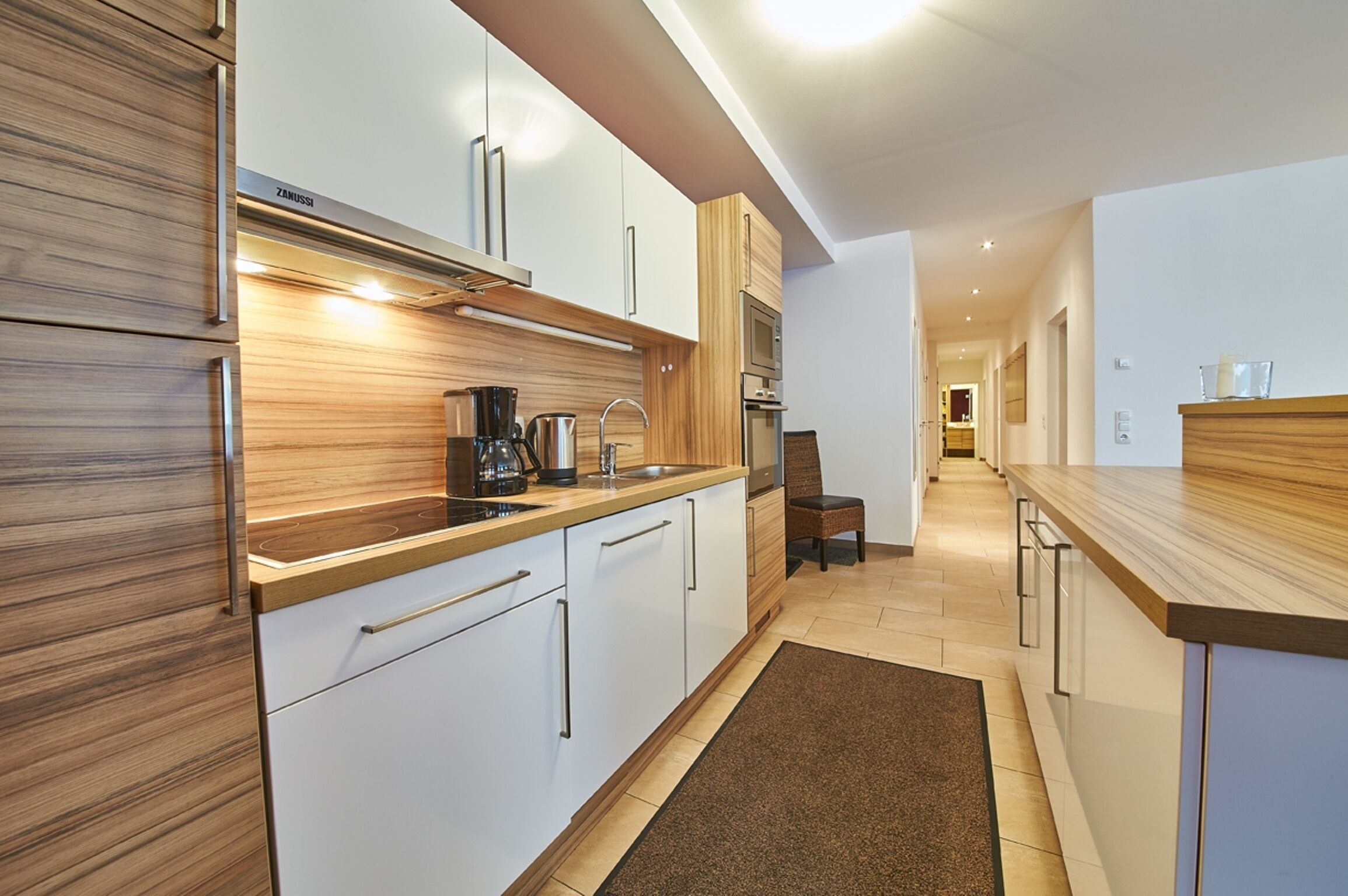 Eine moderne Küche mit weißen Schränken, einer Holz Arbeitsplatte und einer eingebauten Mikrowelle.
