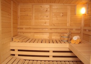 A wooden sauna with benches and a bench seat. - Cozy apartment with sauna (Saalbach)