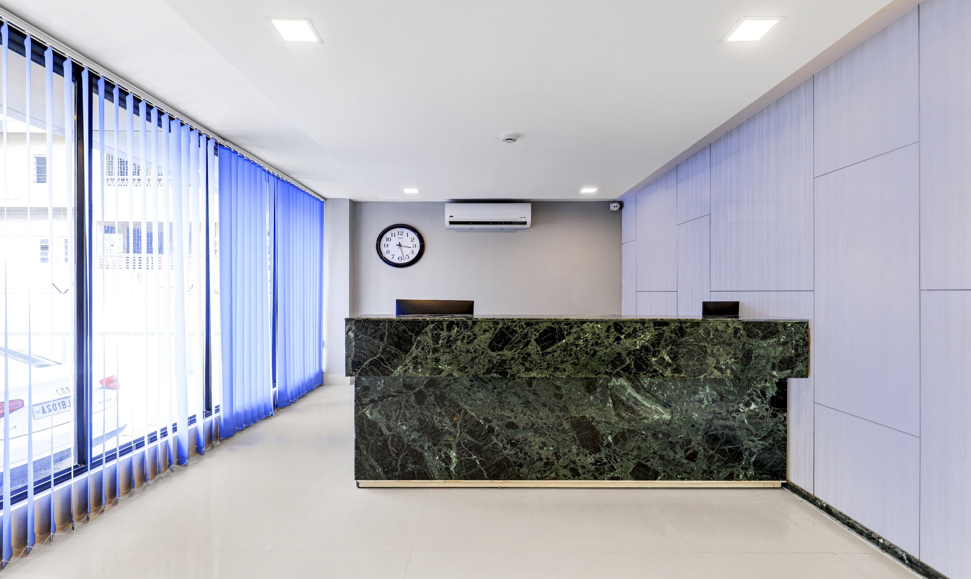 A reception desk with a marble top, a clock, and an air conditioning unit on the wall.