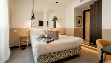 A neatly arranged hotel room with a large bed, bedside tables, a chair, and a mirror.