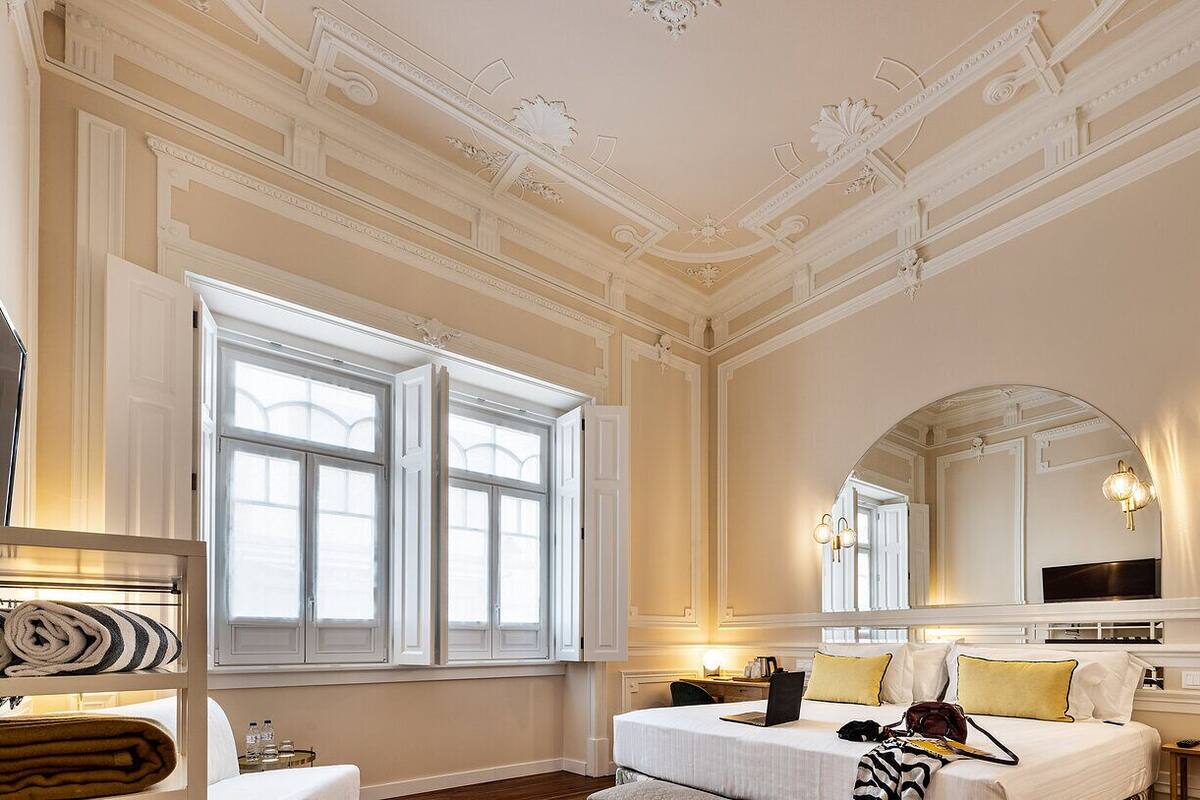 A hotel room with a large bed, a mirror, a television, and a window with curtains.