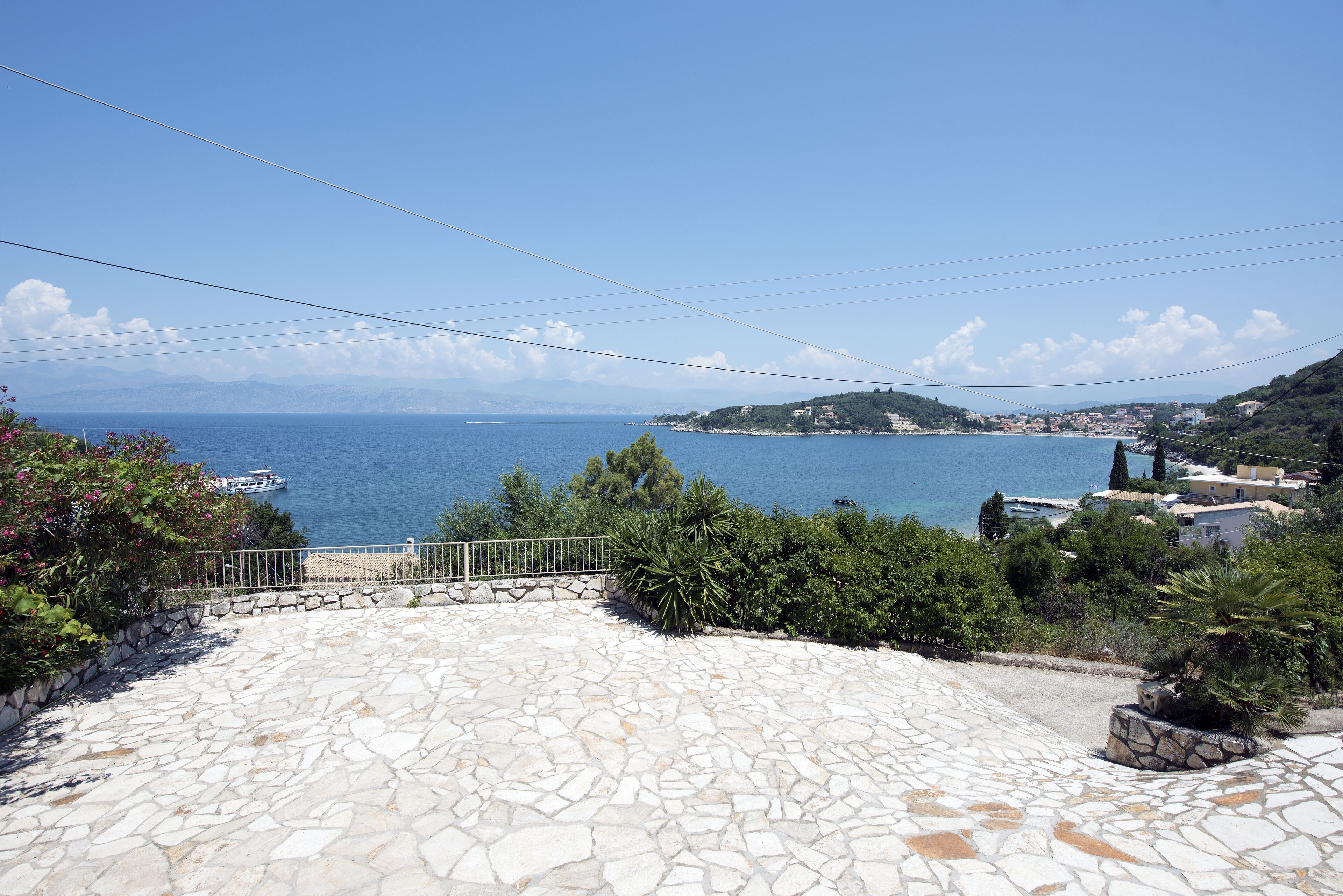 Une terrasse dallée de pierres, offrant une vue sur la mer et une île lointaine.