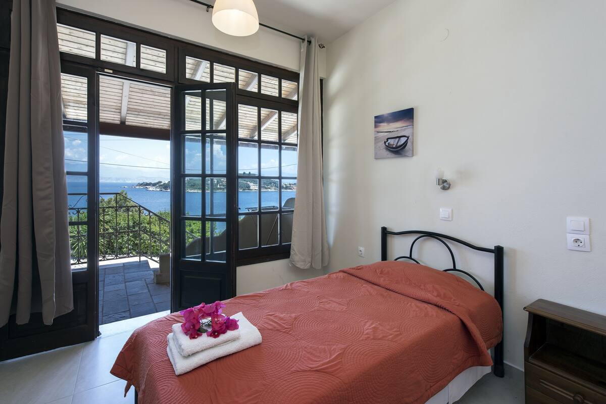 Une chambre avec un lit, une vue sur la mer et un balcon.