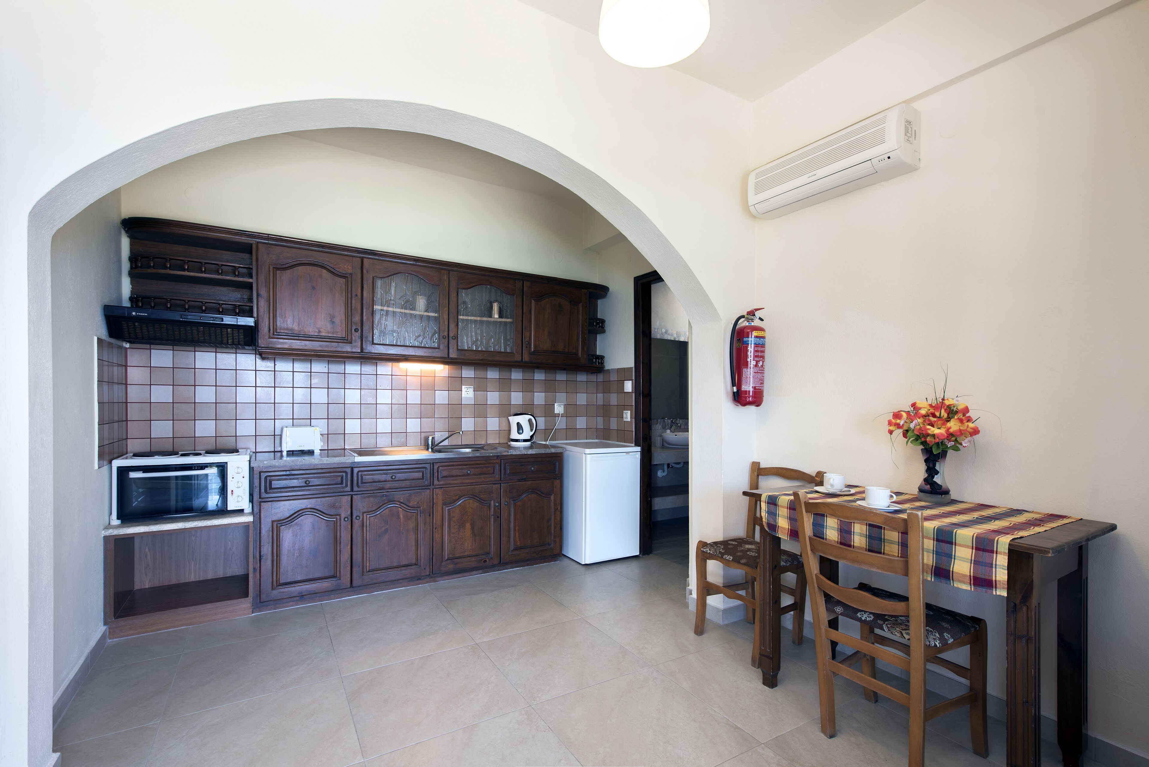 A kitchen with wooden cabinets, a microwave, a sink, and a dining table with chairs.