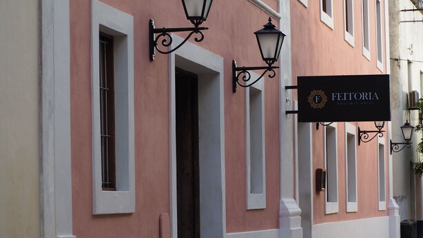 Un edificio con un cartel que dice 'FEITORIA Boutique Hotel'.