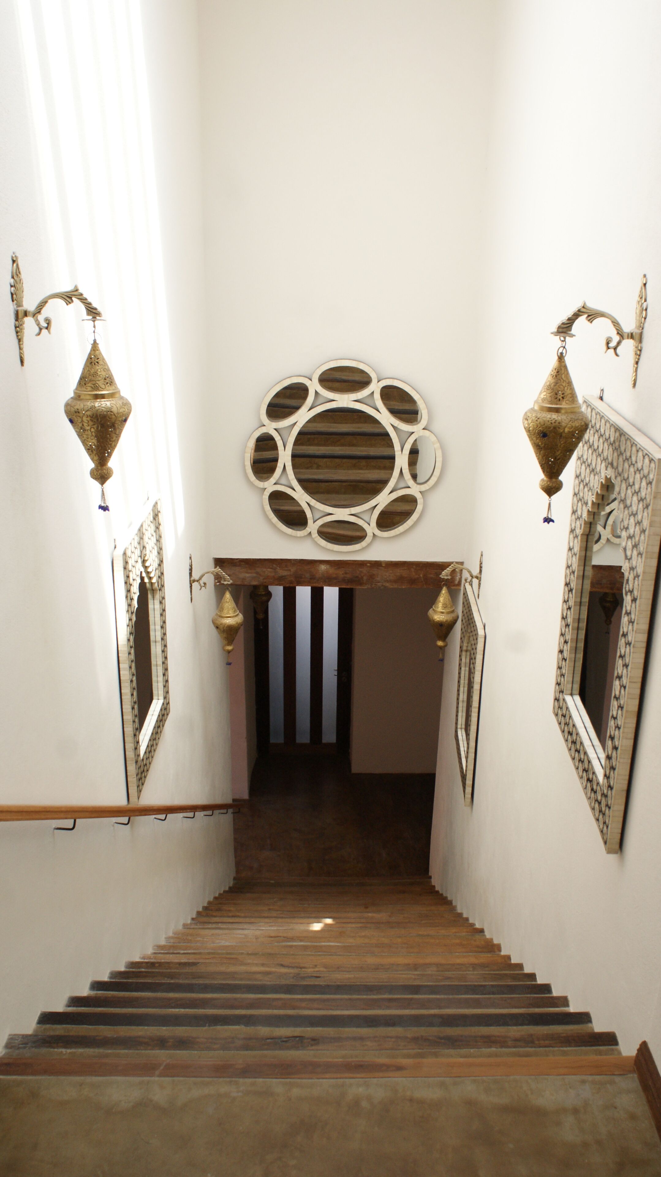A staircase with ornate wall sconces and a decorative mirror at the top.