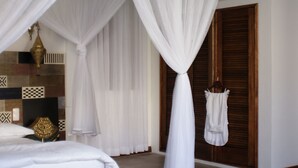 A bedroom with a bed, a canopy, a patterned rug, and a wooden ceiling. - Feitoria Boutique Hotel (Mozambique Island)