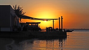 A waterfront building with a patio overlooking the sea during sunset. - Feitoria Boutique Hotel (Mozambique Island)