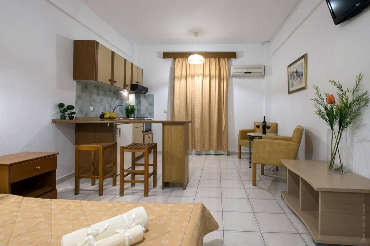 A compact hotel room with a kitchenette, a dining area, and a bed.