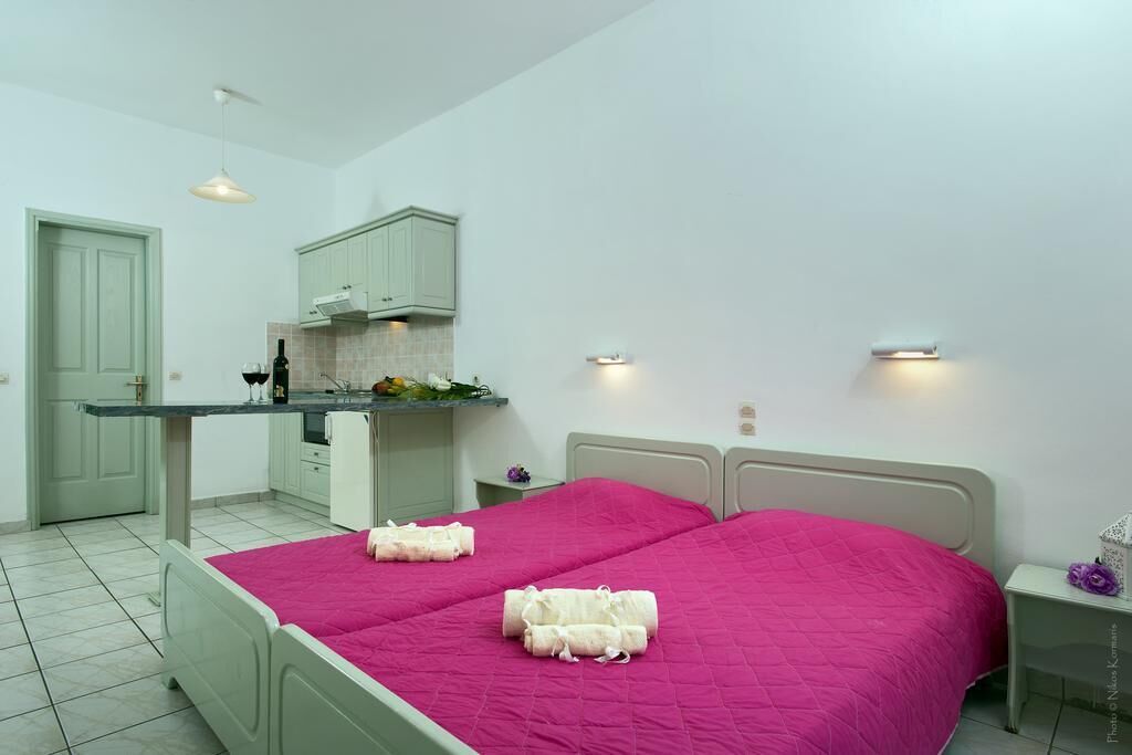 Un dormitorio con dos camas, una kitchenette pequeña y un baño.