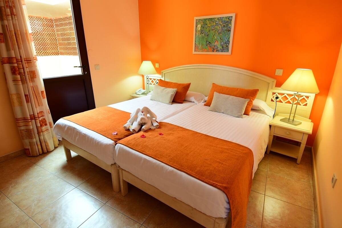 Una cama doble con dos almohadas, una mesita de noche con lámpara y un cuadro en la pared.