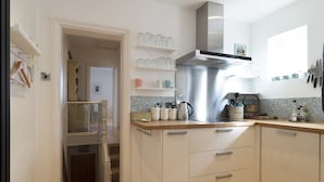 A modern kitchen with white cabinets, a stainless steel range hood, and a tiled backsplash. - Sail Away - 2-Bed Apartment by the Beach (Whitstable)