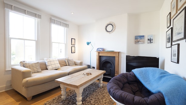 A living room with a sofa, a coffee table, a fireplace, and a television. - Sail Away - 2-Bed Apartment by the Beach (Whitstable)