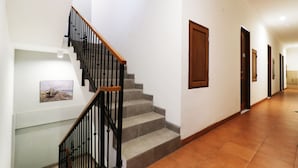 A hallway with a staircase, wooden doors, and a framed picture on the wall. - Nikara Residence Syariah (Jakarta)