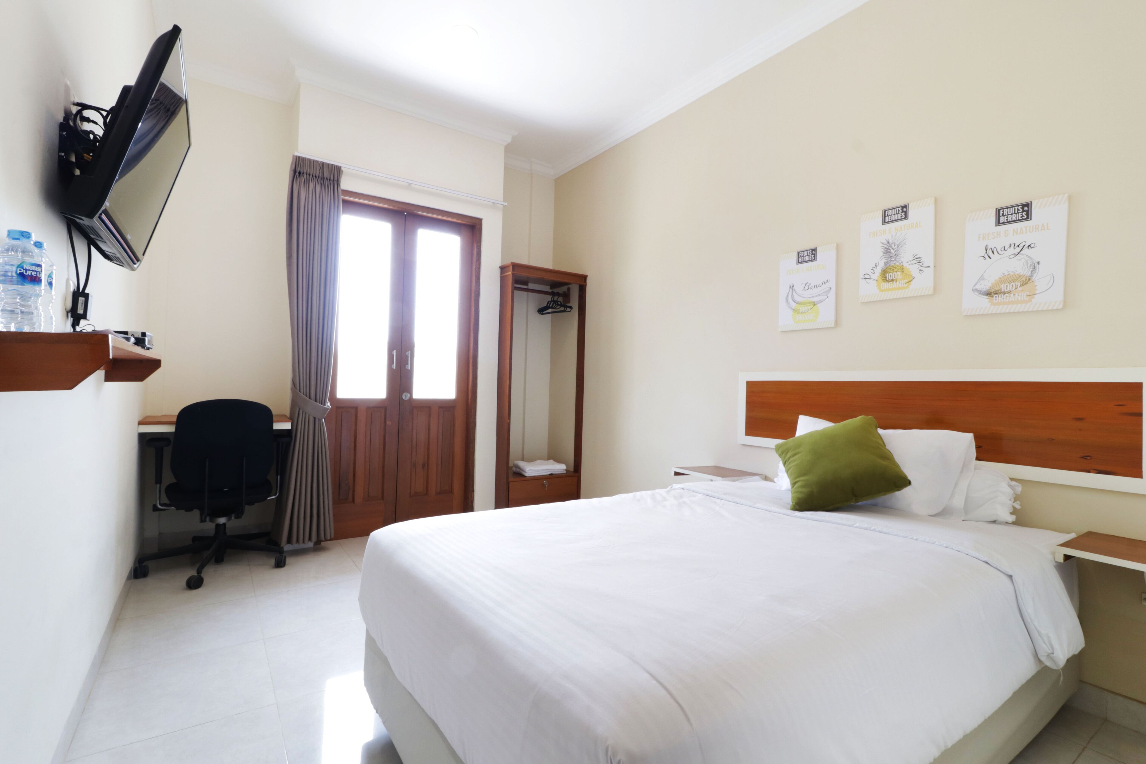 Ein Hotelzimmer mit Bett, Schreibtisch, Sessel, Fernseher und Kleiderschrank.