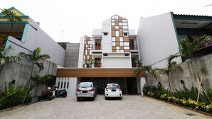 A modern building with a garage entrance, two parked cars, and a motorcycle. - Nikara Residence Syariah (Jakarta)