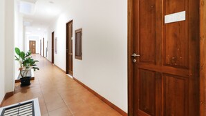 A hallway with wooden doors, a potted plant, and a vent. - Nikara Residence Syariah (Jakarta)