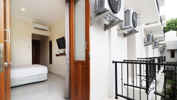 A hotel room with a bed, a TV, and an air conditioning unit. - Nikara Residence Syariah (Jakarta)