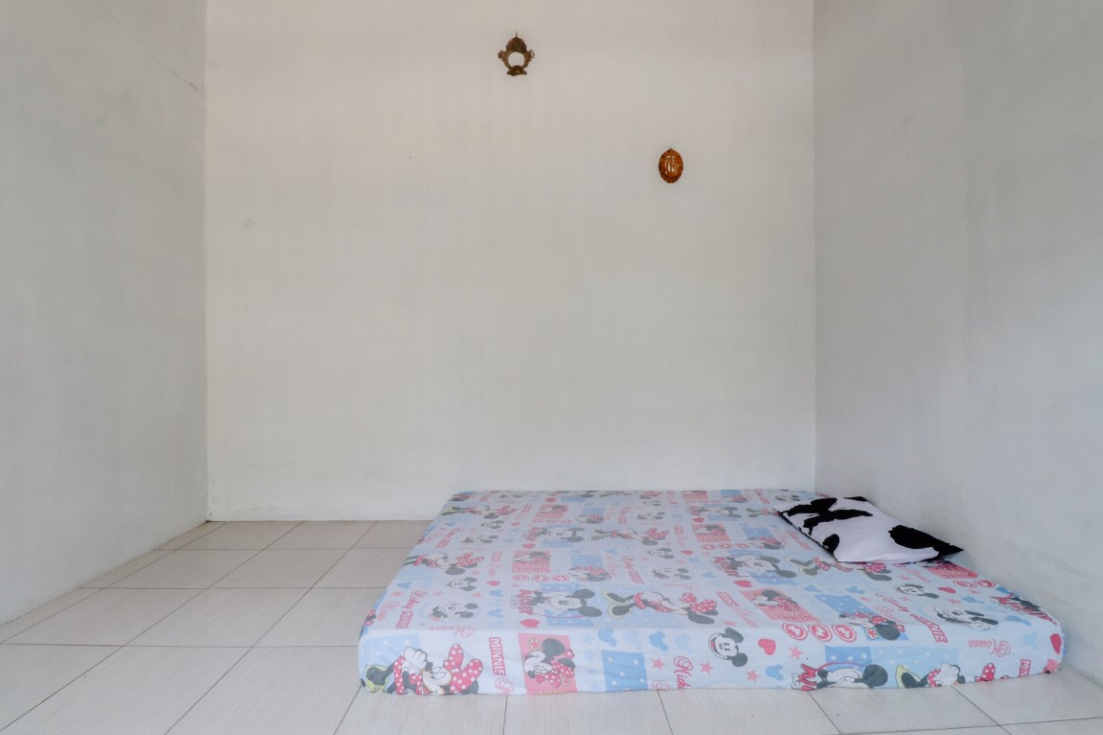 A small, empty room with a single bed and a pillow.