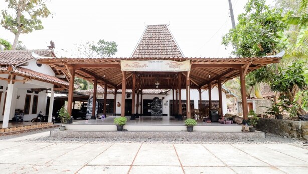 A traditional pavilion with a tiled roof, surrounded by potted plants and a stone pathway. - Griya Erlangga Homestay (Bantul)