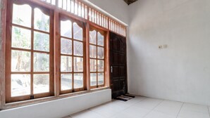 A room with large windows, a tiled floor, and a dark door. - Griya Erlangga Homestay (Bantul)