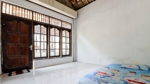 A room with a large window, a wooden door, and a bed with a Doraemon-themed bedspread. - Griya Erlangga Homestay (Bantul)