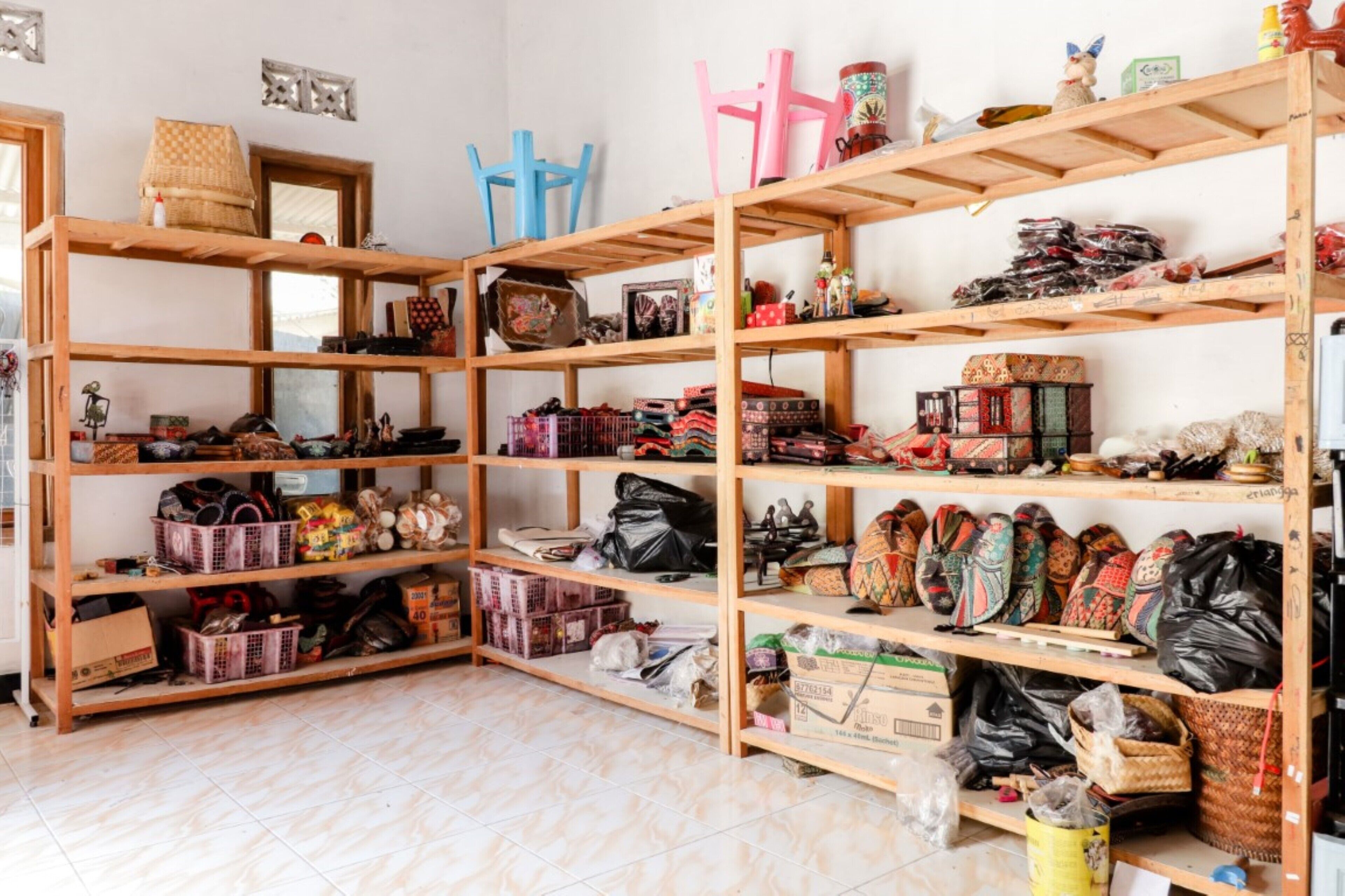 A storage room with wooden shelves filled with various items, including baskets, boxes, and bags.