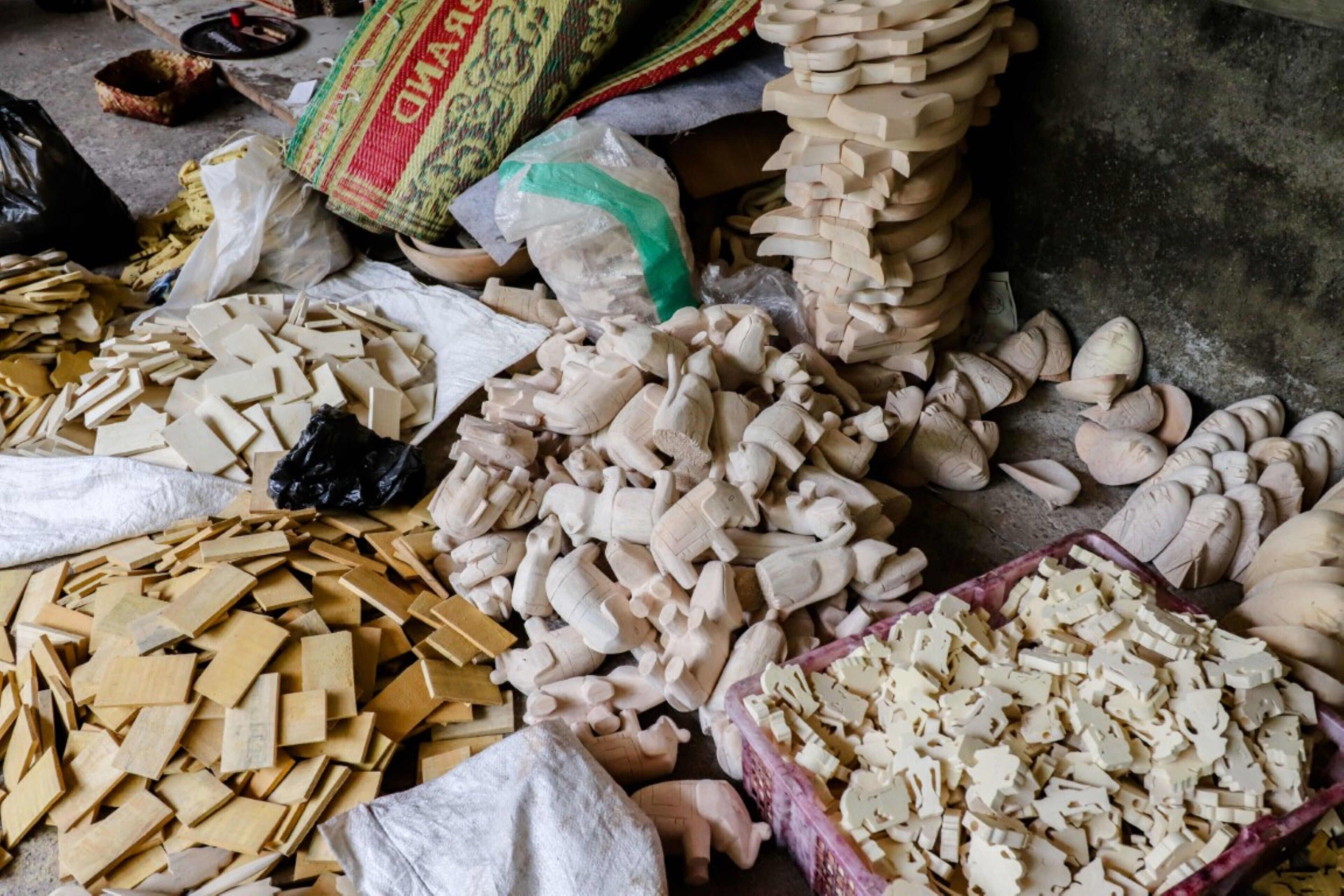 A collection of wooden blocks and pieces on the floor, surrounded by bags and sacks.