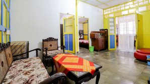 Habitación con sofá, una mesa y televisor. Hay puertas que dan a otras habitaciones.