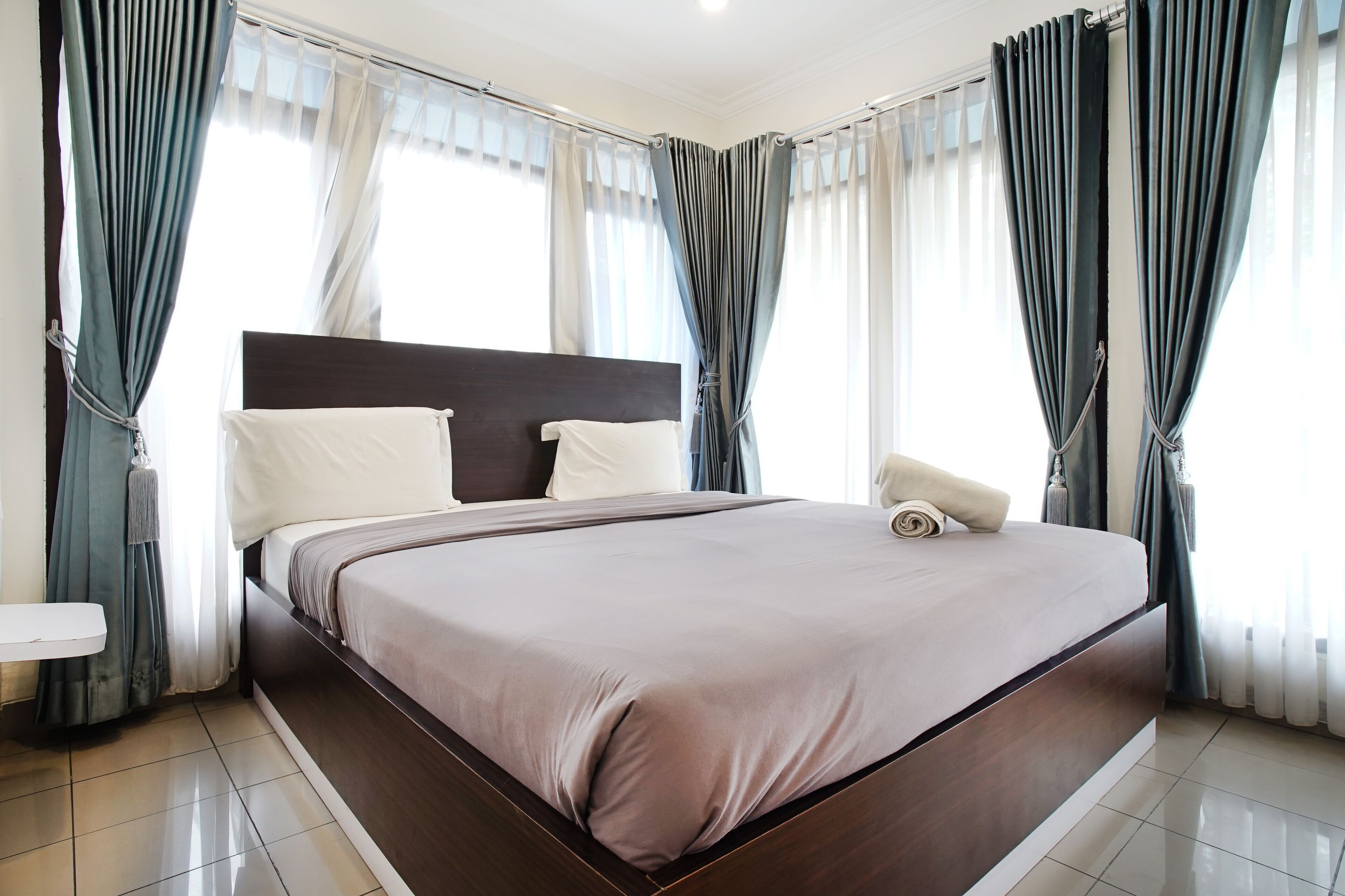 Una habitación de hotel moderna con una cama grande, un cabecero de madera y una mesita de noche.