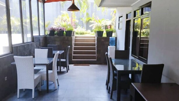 Un espace patio intérieur avec une table et des chaises en verre, un escalier menant à un jardin et un distributeur d’eau.