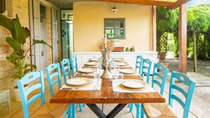 A covered outdoor dining area with a wooden table set for six, surrounded by blue chairs, and a white cabinet in the background. - Large historic villa with pool, panoramic views surrounded by greenery (Ostra)
