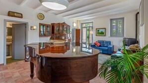 A spacious living area with a large wooden coffee table, a blue sofa, and a television. - Large historic villa with pool, panoramic views surrounded by greenery (Ostra)