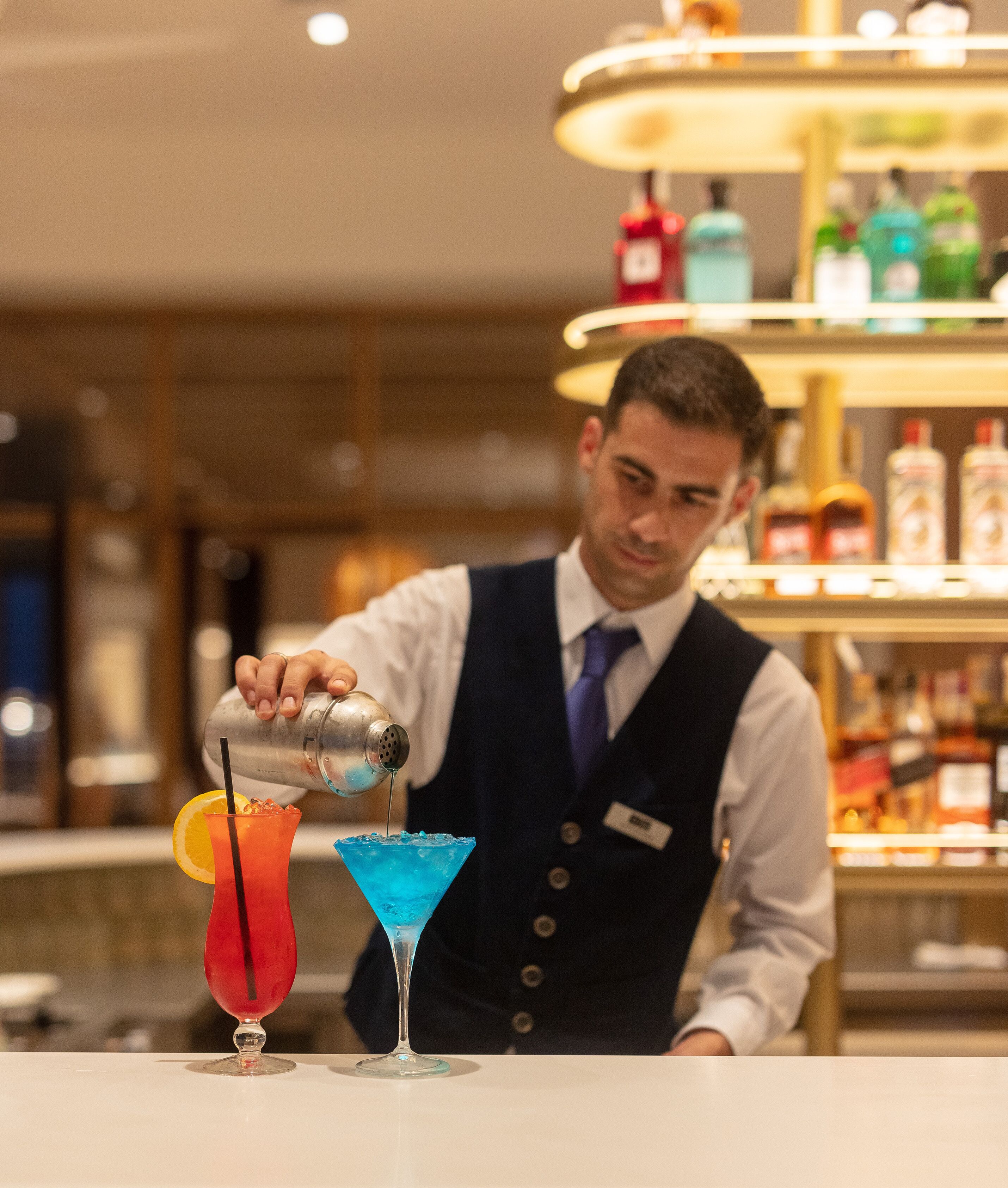 Un barista versa un drink in un bicchiere da martini.