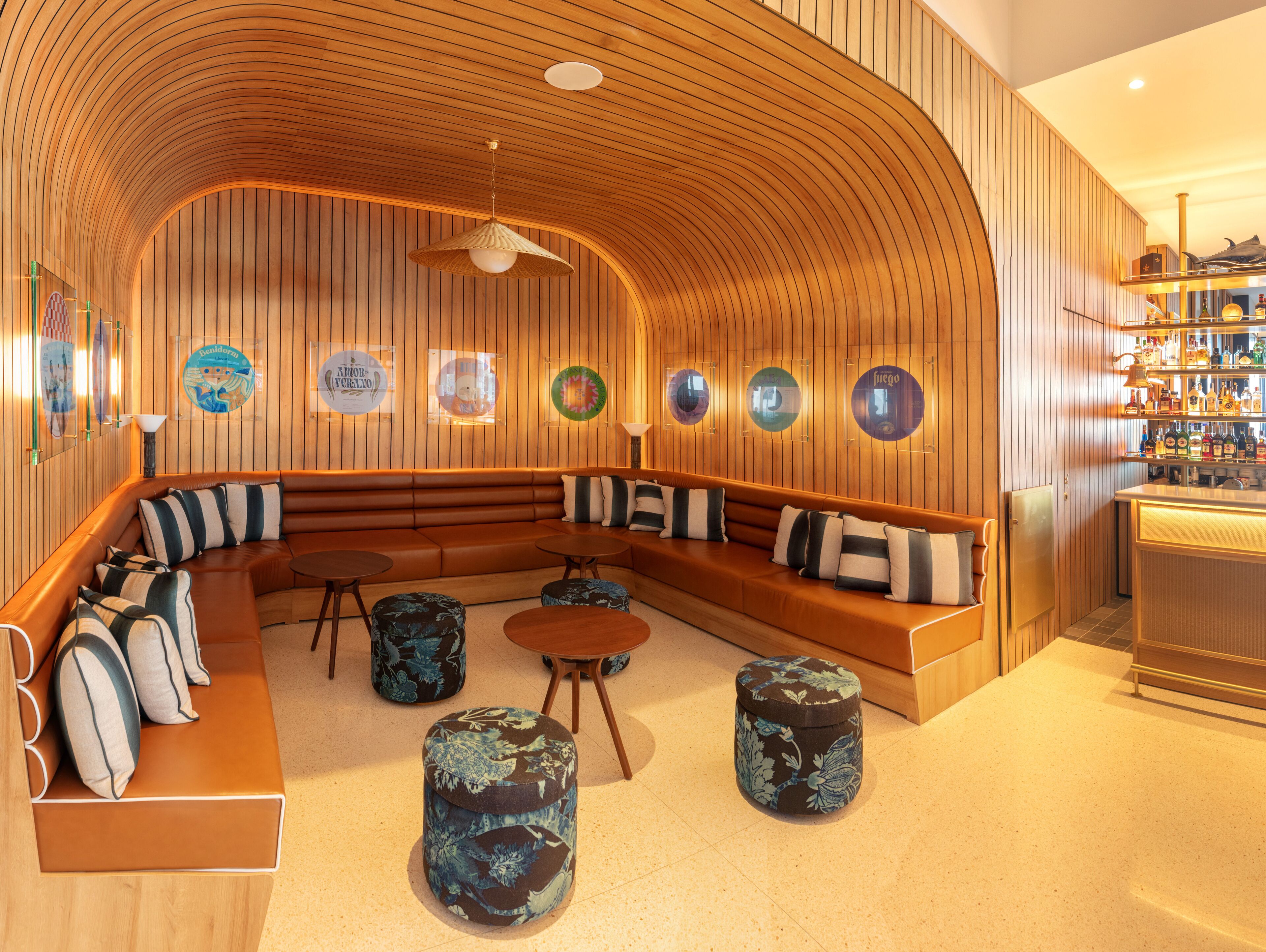 Et moderne loungeområde med et buet træloft, læderpolstret møbler og en bar med et udvalg af flasker.