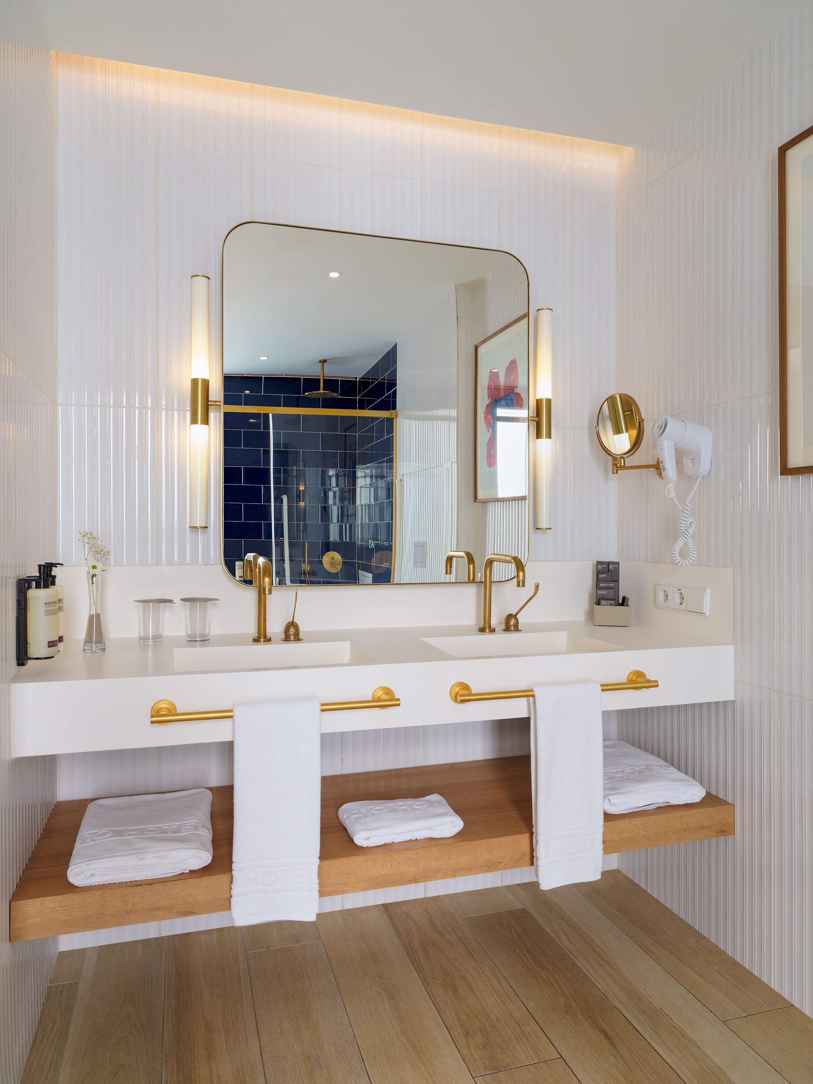 A modern bathroom with a white vanity, gold fixtures, and a large mirror.