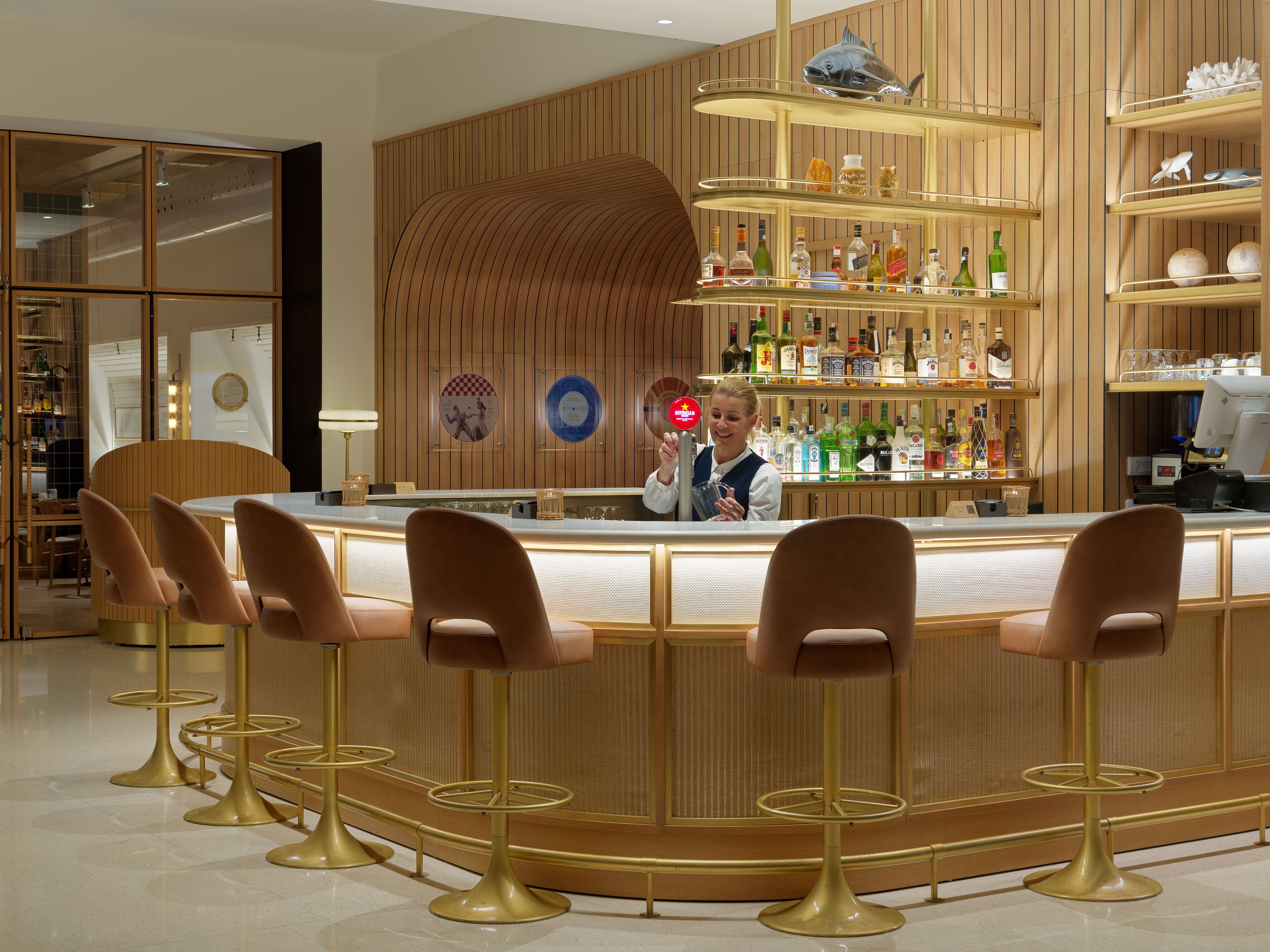 A bar area with a counter, stools, and shelves with bottles.