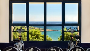 Un gimnasio con dos bicicletas estáticas y vistas al océano a través de amplios ventanales.