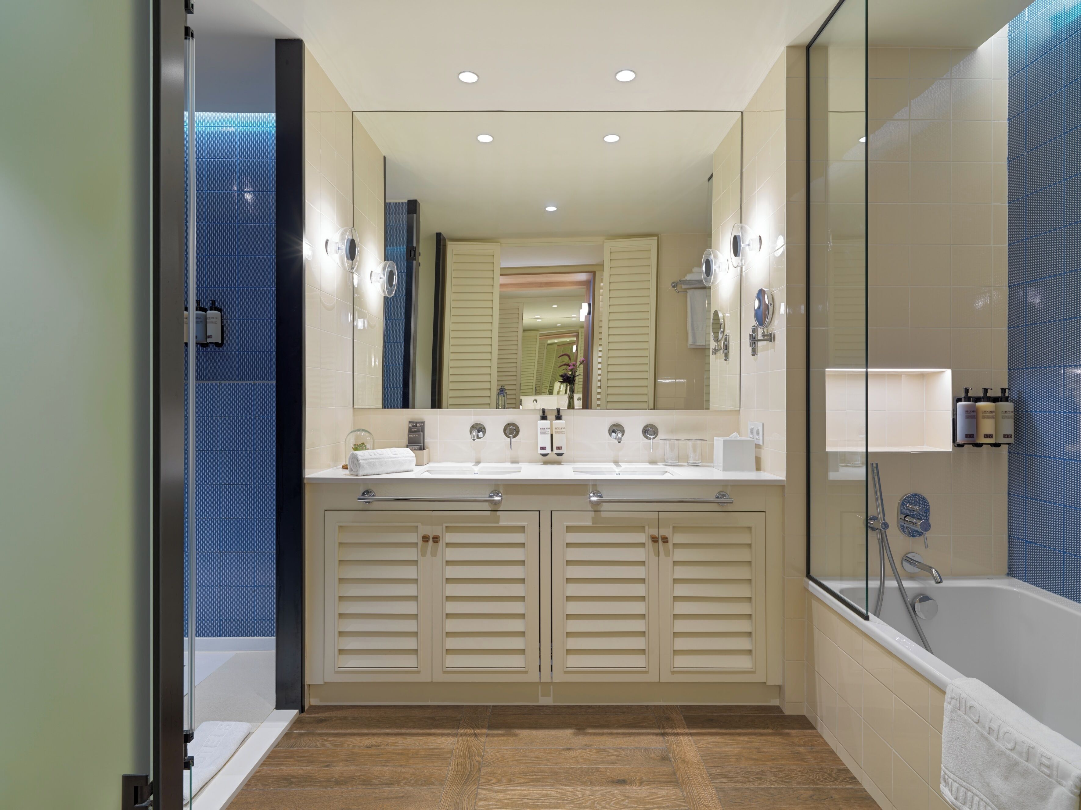A modern bathroom with a double sink vanity, a large mirror, and a bathtub.