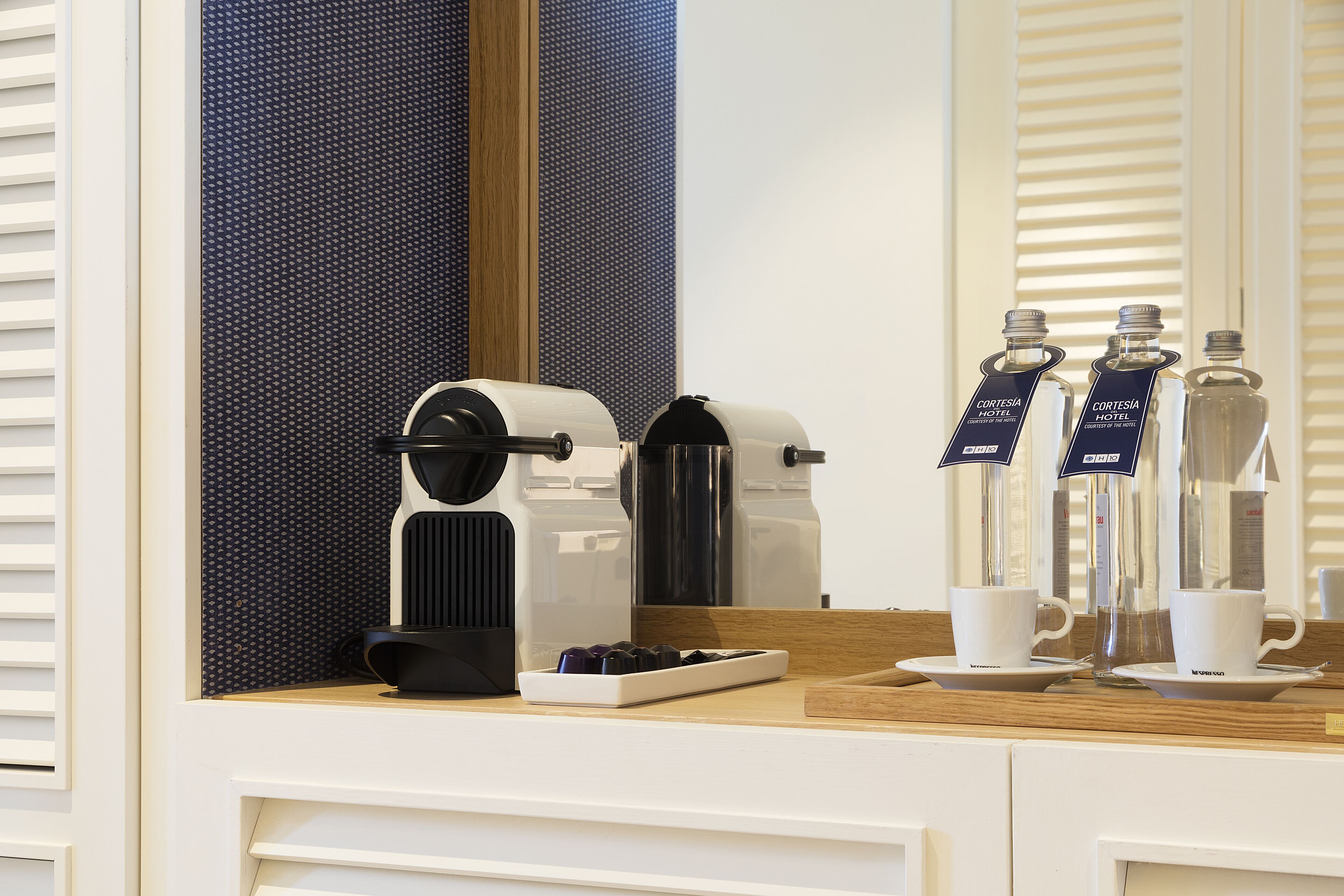 Koffiehoek in een hotelkamer, met een koffiezetapparaat, bekers en waterflessen.
