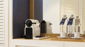 Zona de cafè d'una habitació d'hotel, amb cafetera, tasses i ampolles d'aigua.