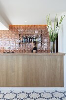 Zona de bar con salpicadero de azulejos, mostrador de madera y un jarrón con flores blancas.
